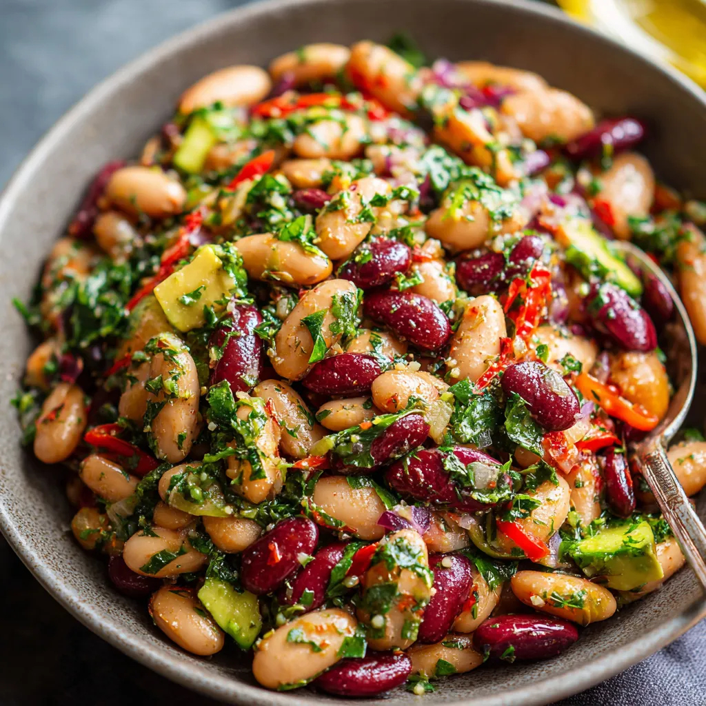 Dense Bean Salad with kidney beans, white beans, avocado, herbs, and zesty dressing in a serving bowl.