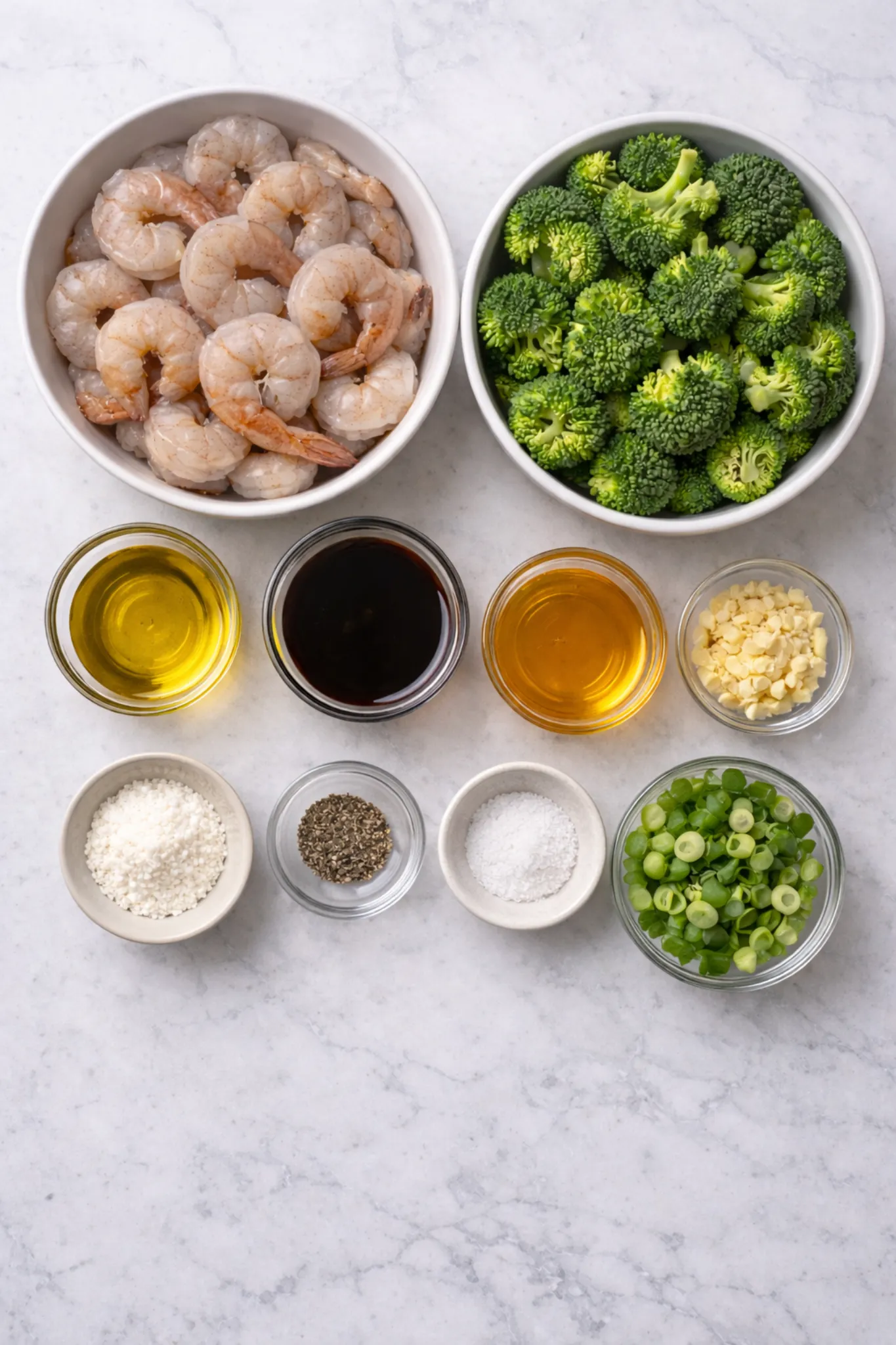 Fresh ingredients for honey garlic shrimp with broccoli arranged neatly in bowls on a light marble surface