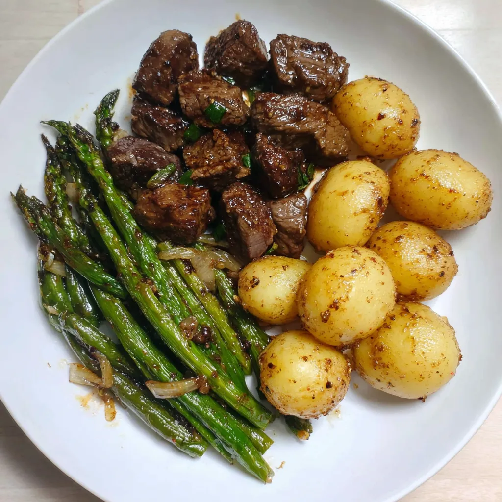 Garlic balsamic steak bites served with roasted baby potatoes and sautéed green beans on a white plate, coated in a glossy balsamic garlic glaze for an easy dinner or meal prep