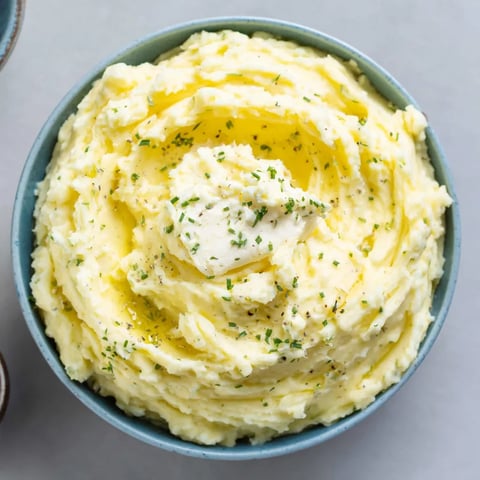 A bowl of mashed potatoes with a dollop of cream cheese on top.