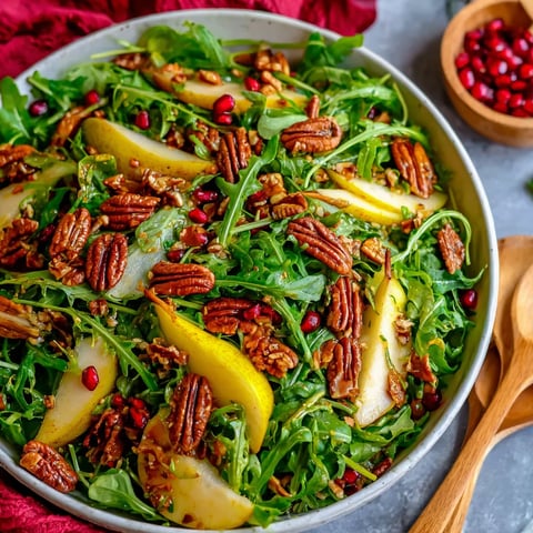 A bowl of salad with arugula, pears, and pecans.
