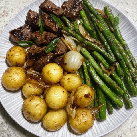 Garlic balsamic steak bites served with roasted baby potatoes and sautéed green beans on a white plate, drizzled with glossy balsamic garlic glaze for a complete meal prep dinner